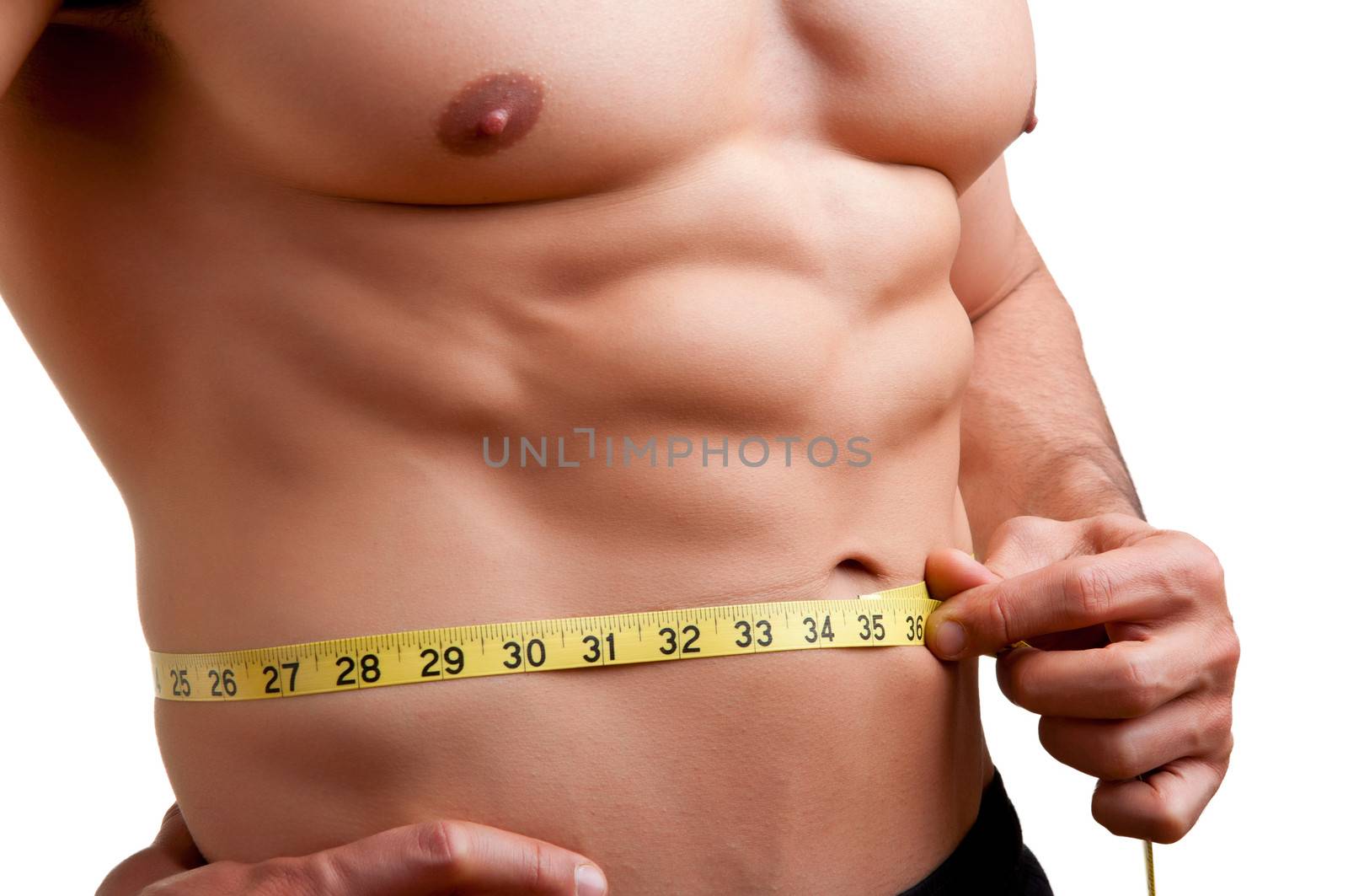 Fit man measuring his waist after a workout in the gym, isolated in a white background