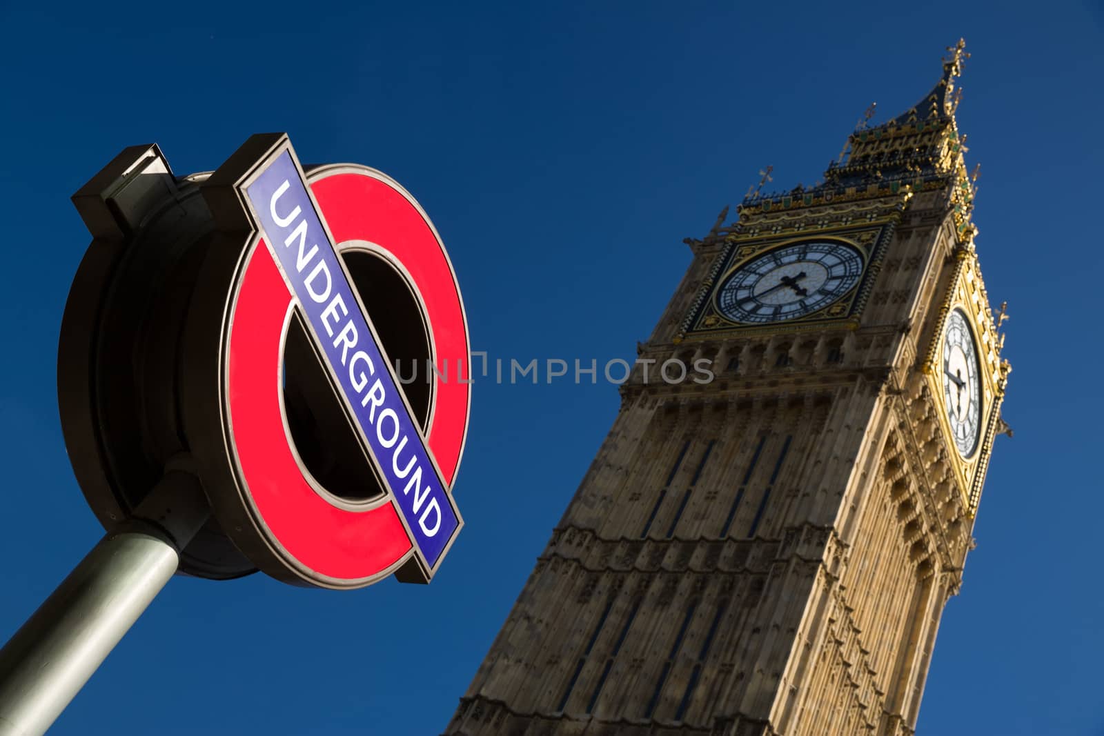 An image of the palace of Westminster with a color image of the underground sign in the foreground