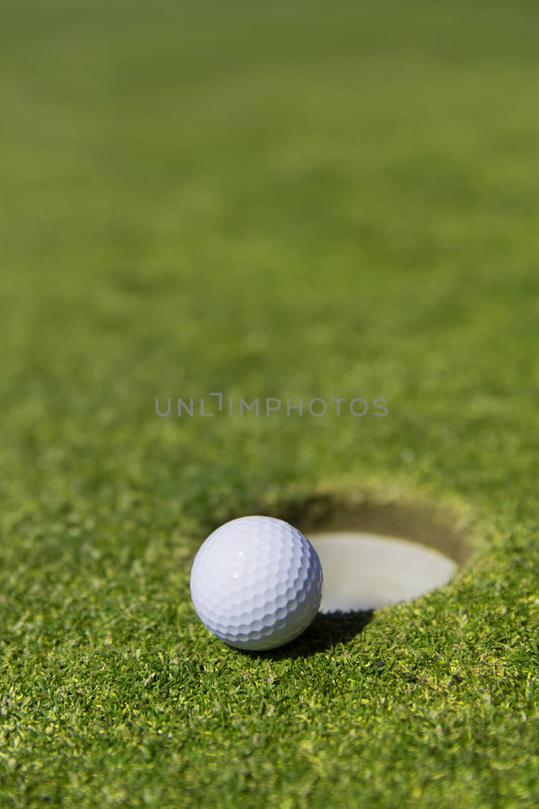 close up of a white golf ball on the edge of a hole with out a flag