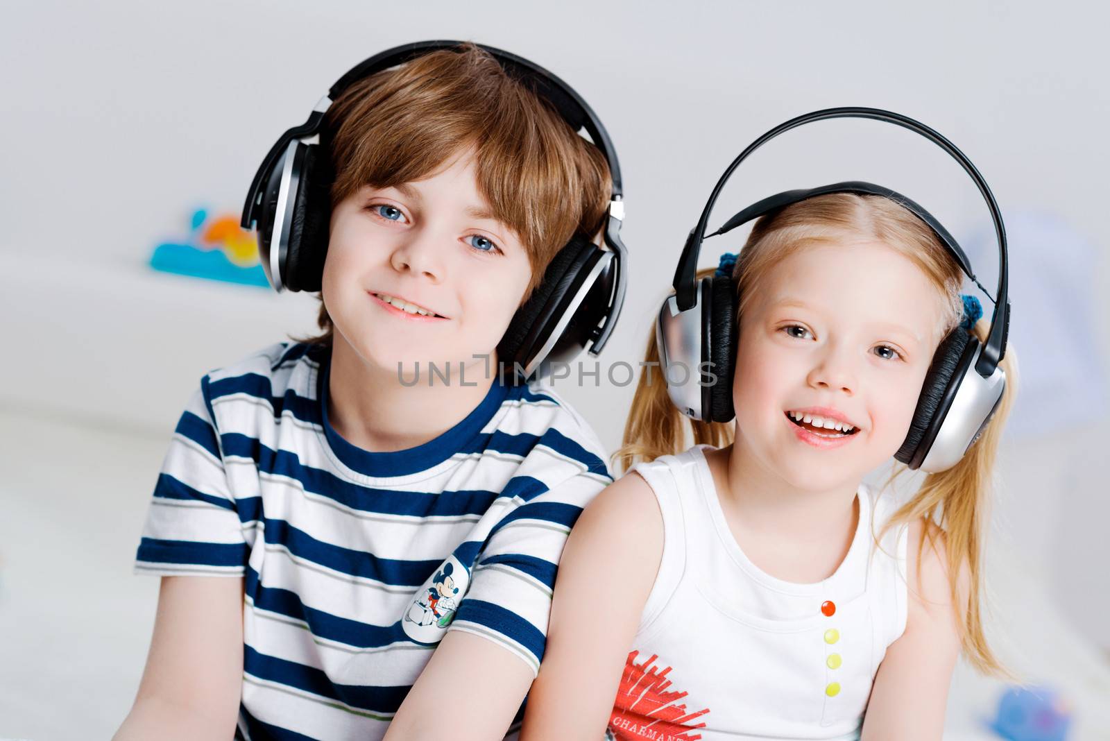 brother and sister listen to music in the living room with headphones