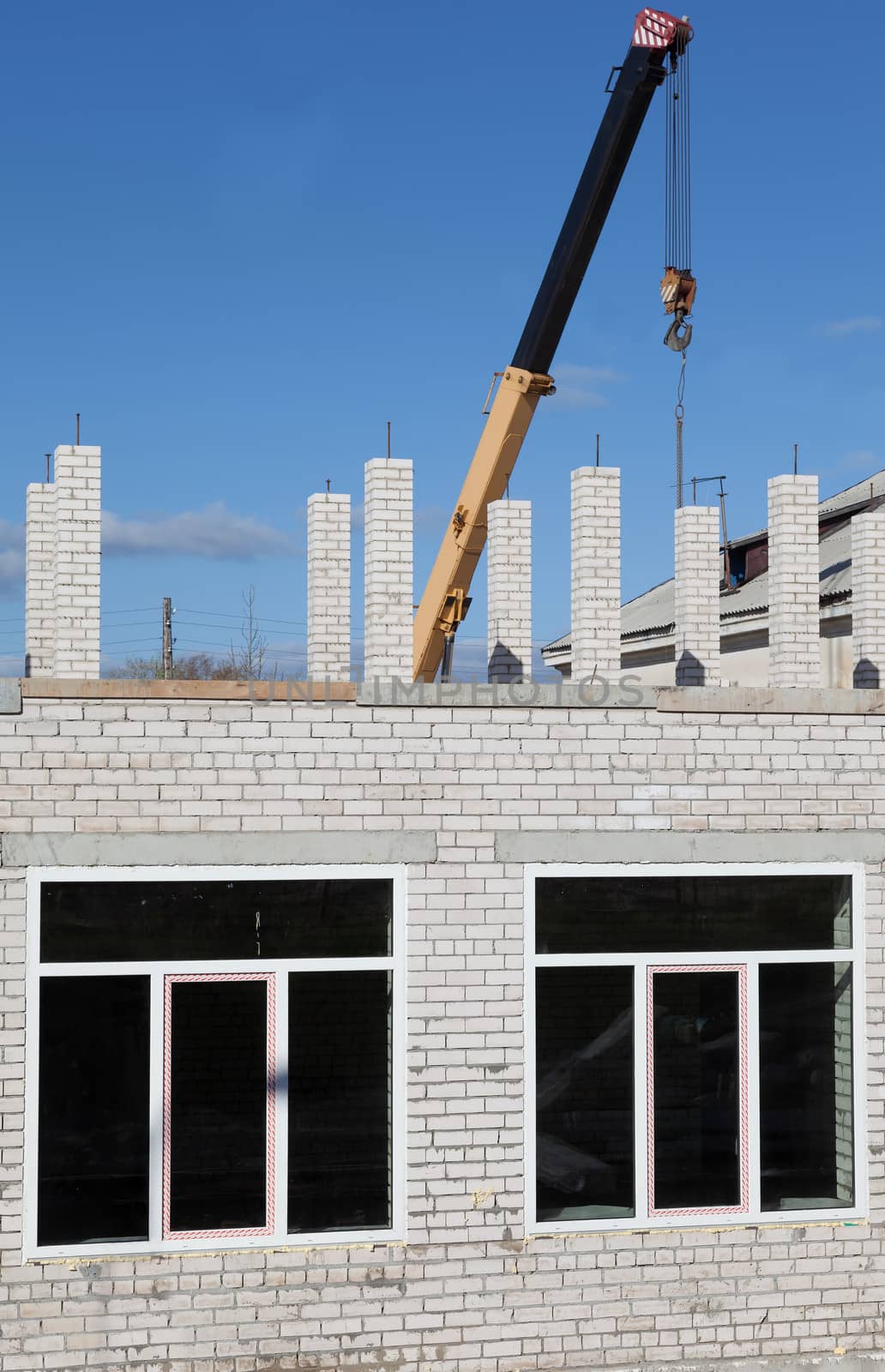 Building a house out of gray bricks using a crane