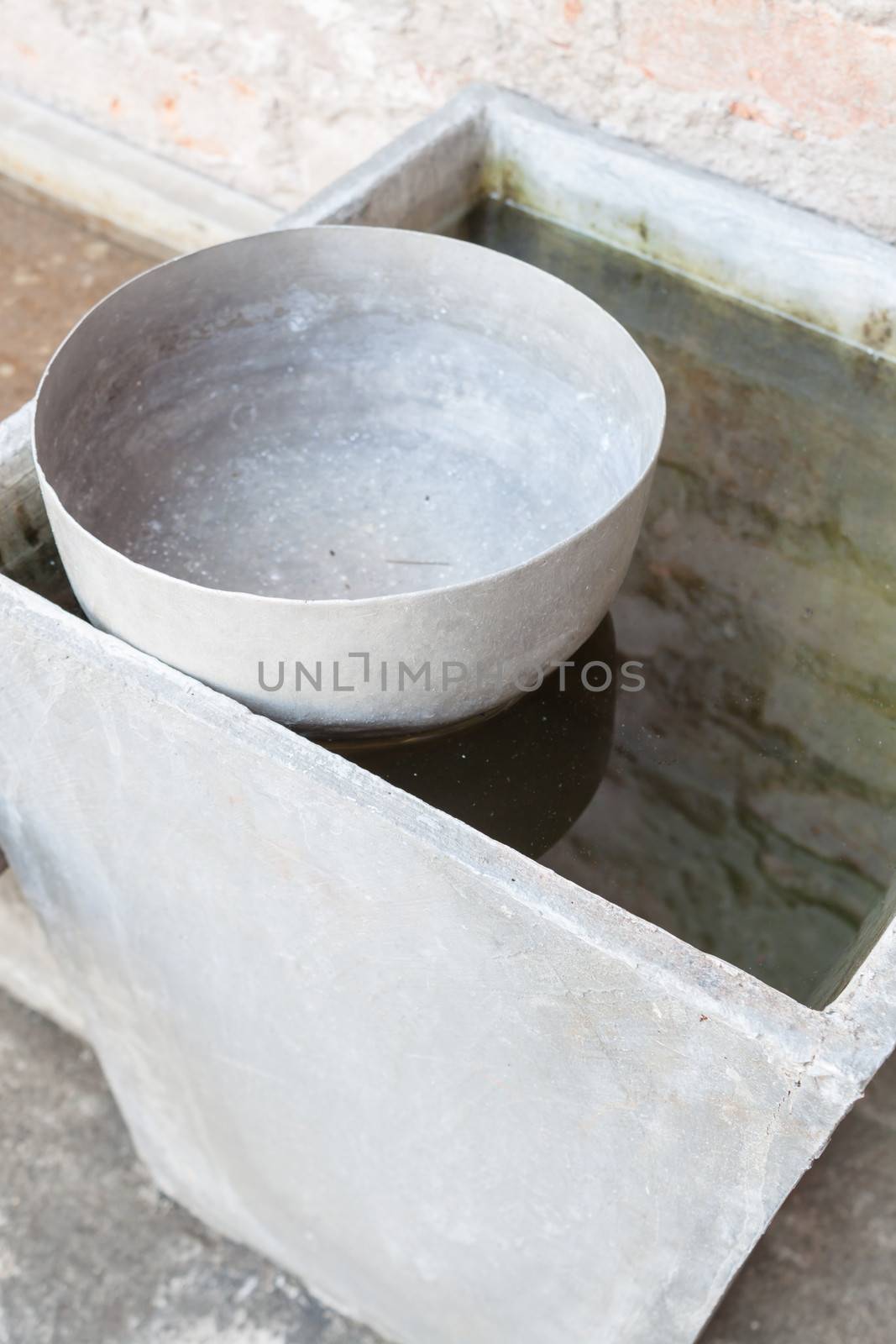 Single old stainless water bowl surrounded by water