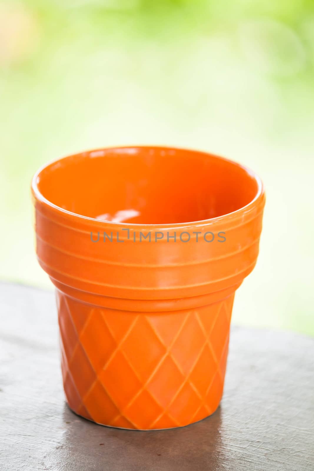 Orange ceramic plant pot with green bokeh by punsayaporn