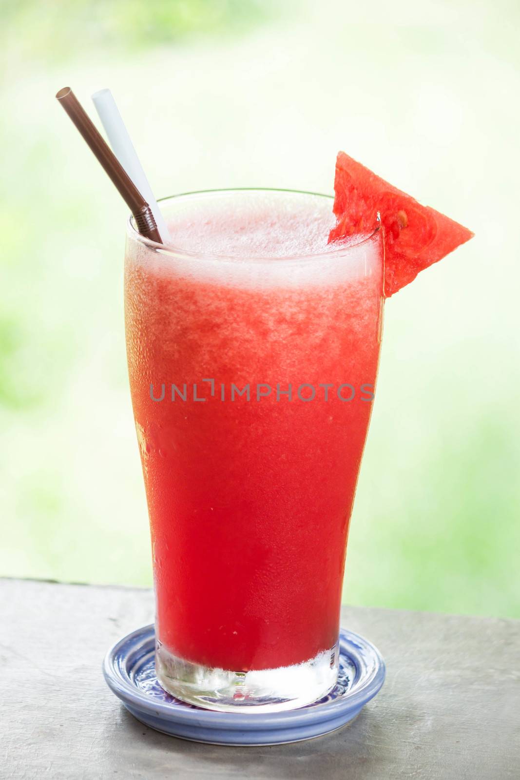 Red water melon fruit juice frappe with green bokeh background by punsayaporn