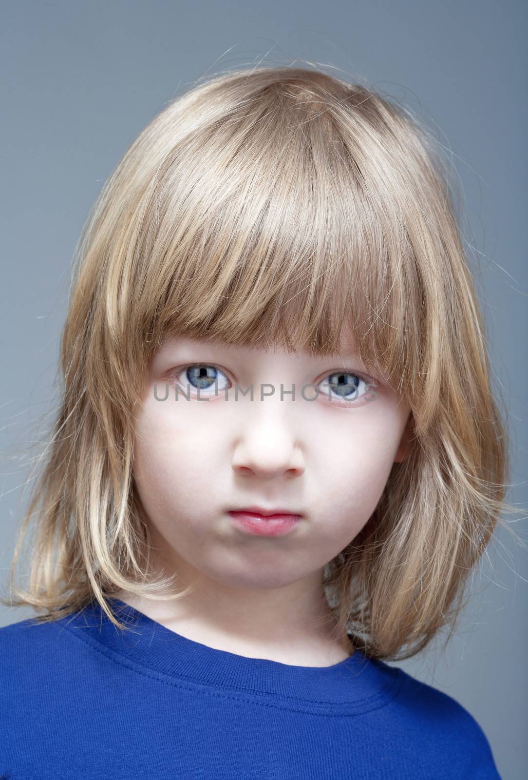 portrait of a boy with long blond hair in blue top - isolated on gray