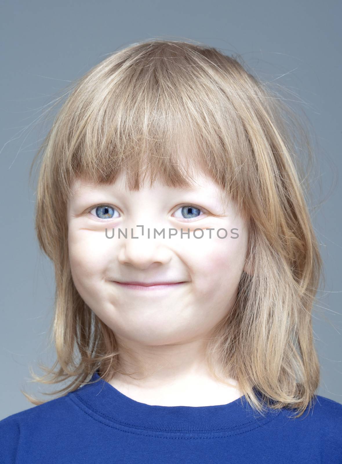 portrait of a boy with long blond hair smiling - isolated on gray