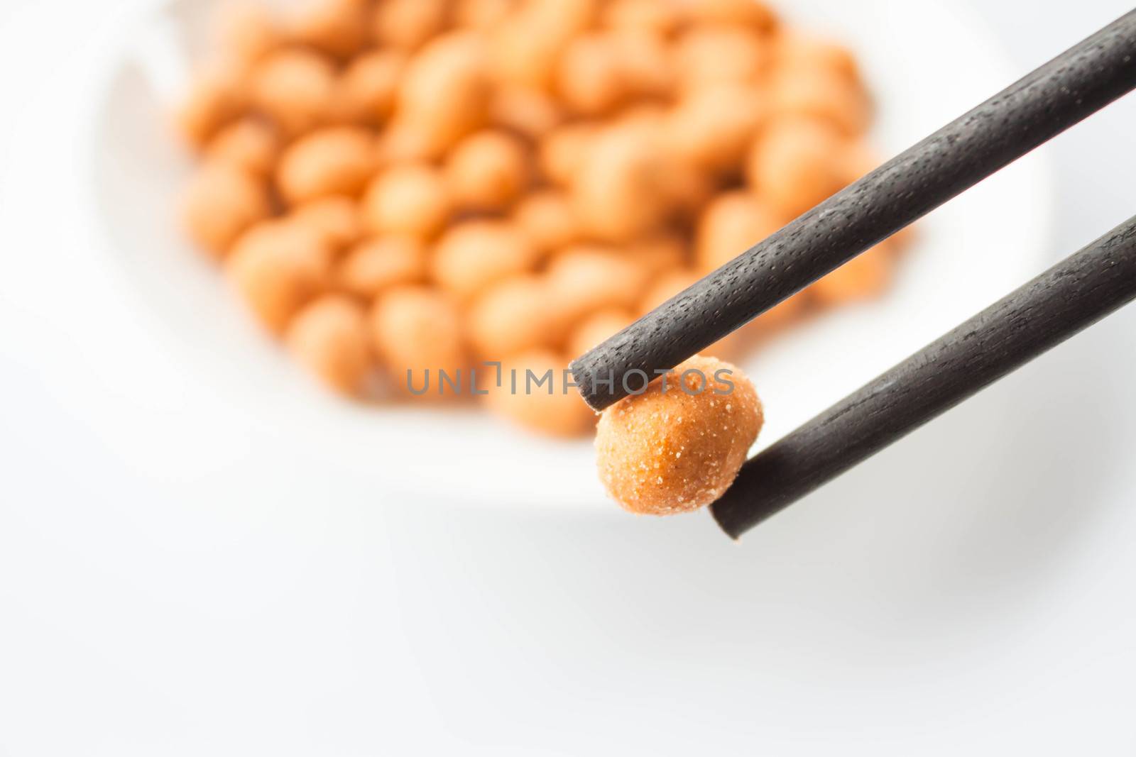 Close up chopstick holding a spicy peanut snack  by punsayaporn