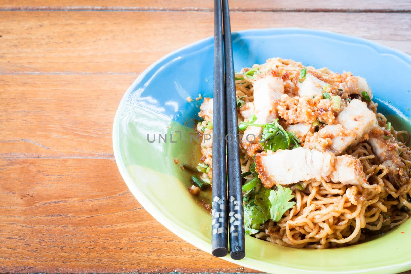 Stir fried spicy noodles with crispy pork and chopstick