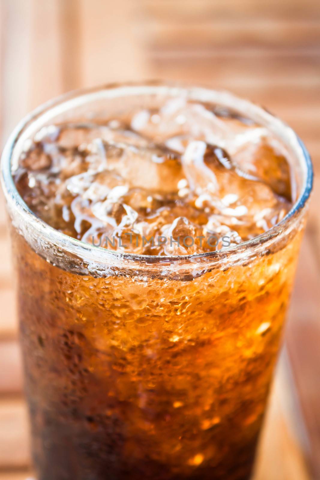 Close up cola drink with ice on wood background