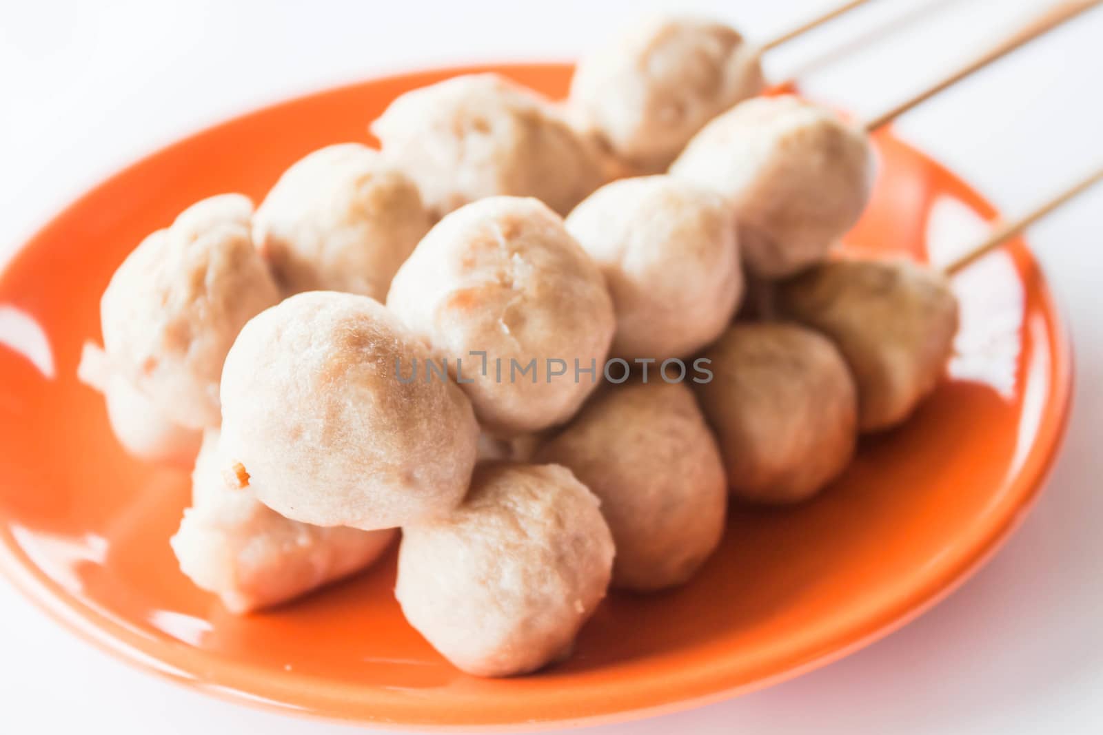 Mini pork balls in orange dish on clean table by punsayaporn