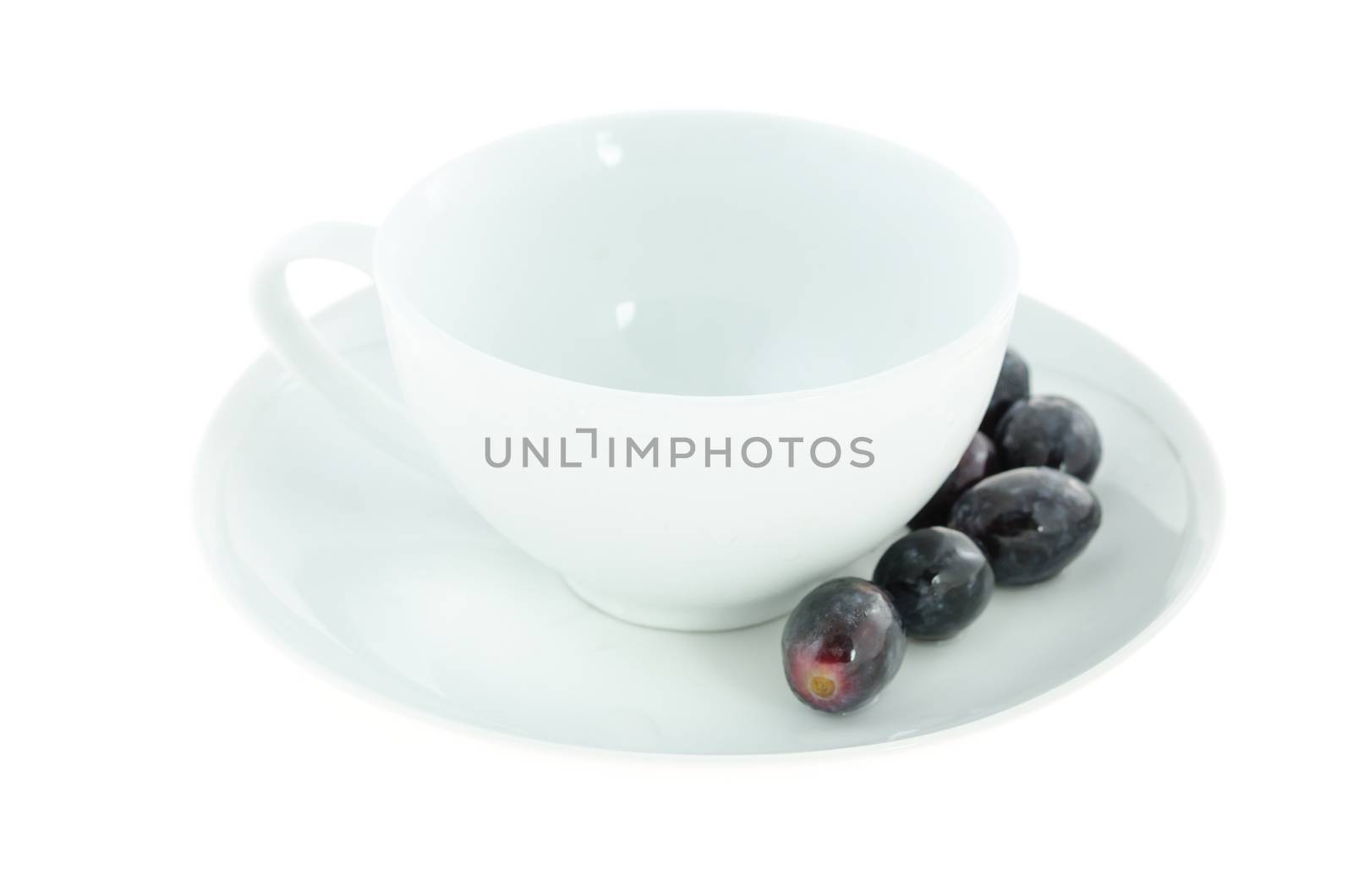 empty white cup and black grapes on plate