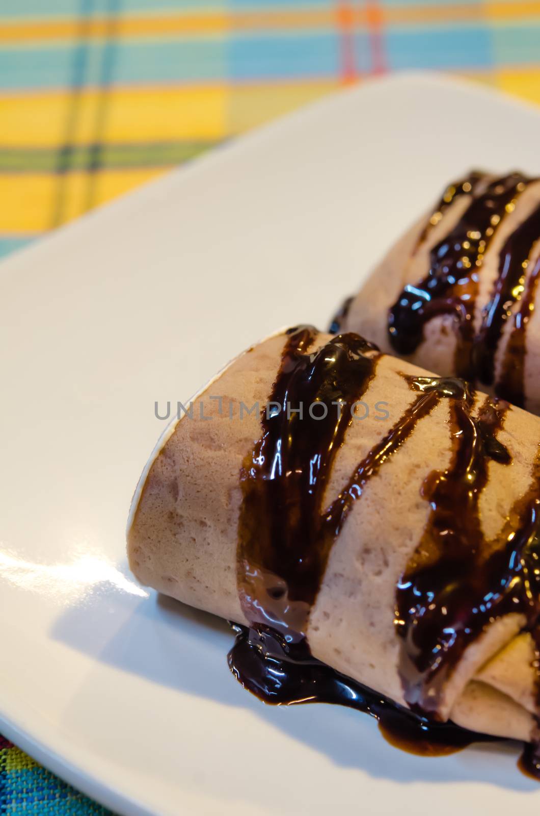 chocolate  crepe rolls  topping with chocolate  syrup on white dish