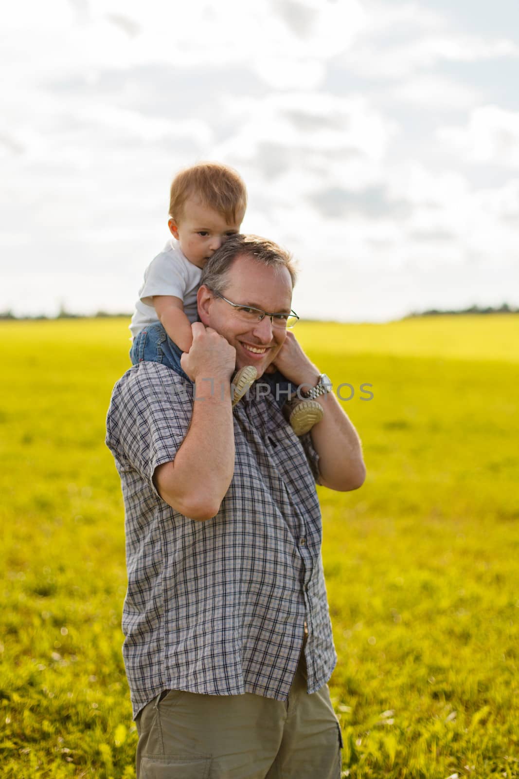 Boy riding his father's shoulders in a field