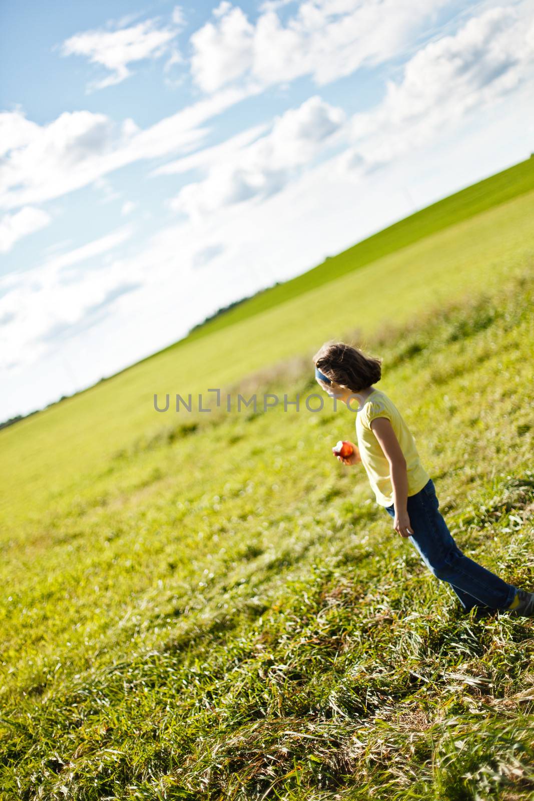 Girl eating an apple in a field near an orchard