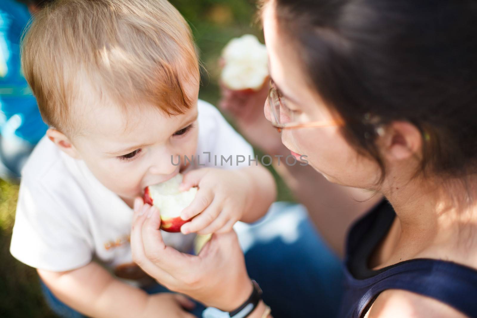 Mother helping her baby eat an apple