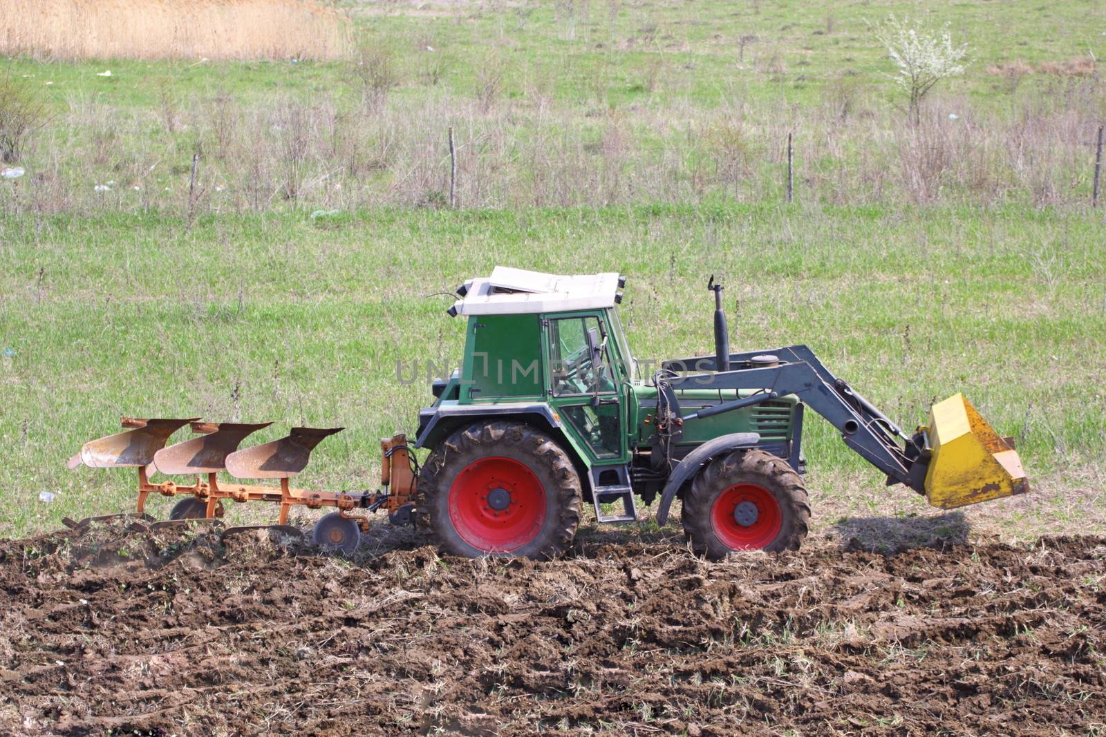 tractor plowing the land in a spring day