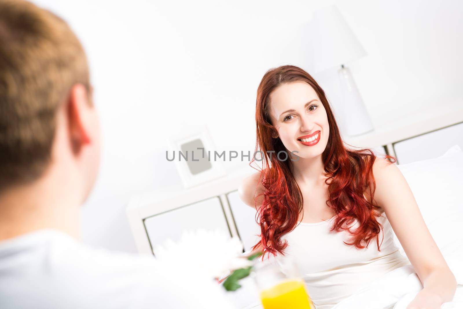 man brought his girlfriend breakfast in bed, holding a tray of juice and breakfast