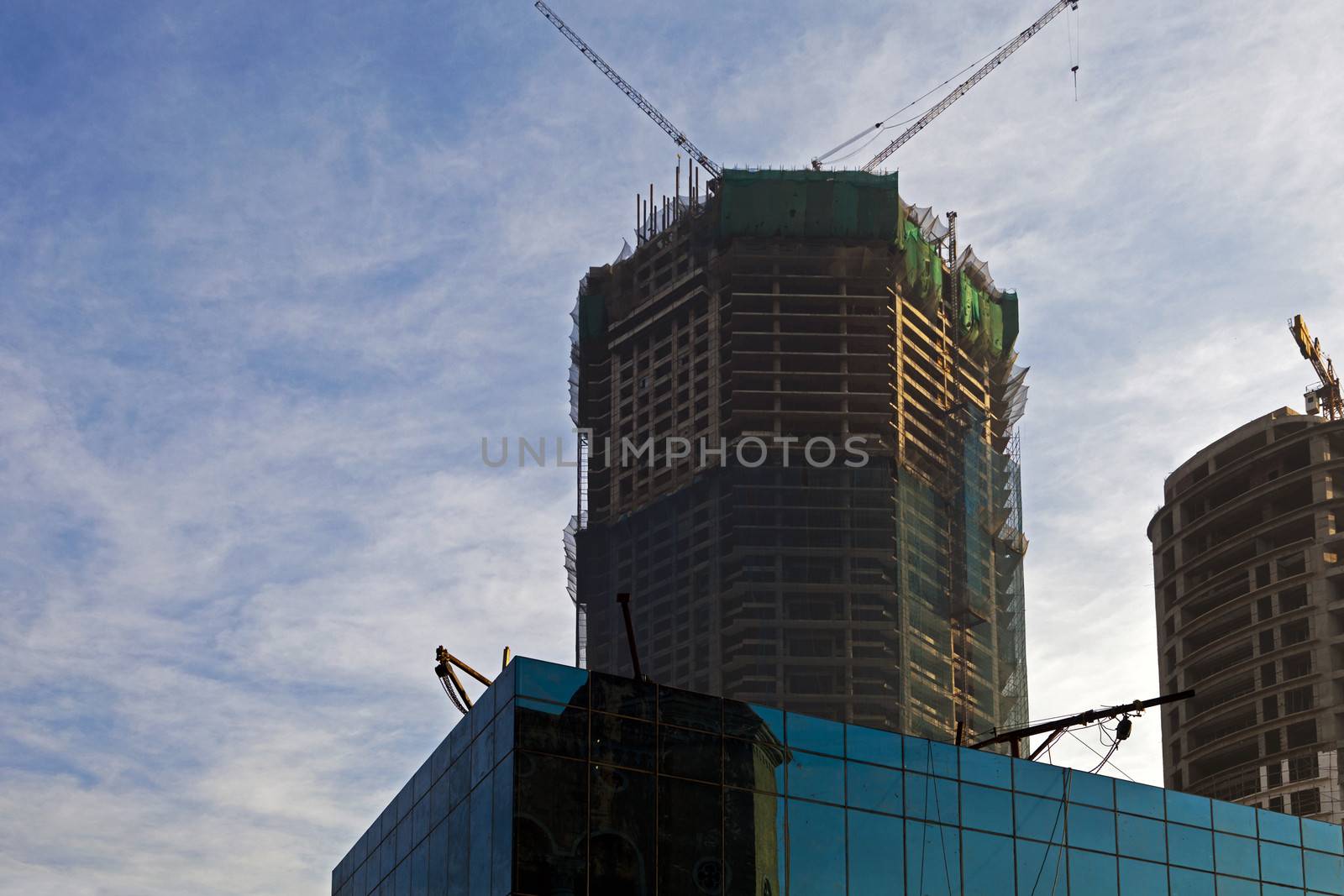 Early morning horizontal color landscape of urban developments, high rise buildings with cranes and lifting gear gantries on terrace tops making bug like shapes. Generic shot taken from an elevated point of view in Bombay India