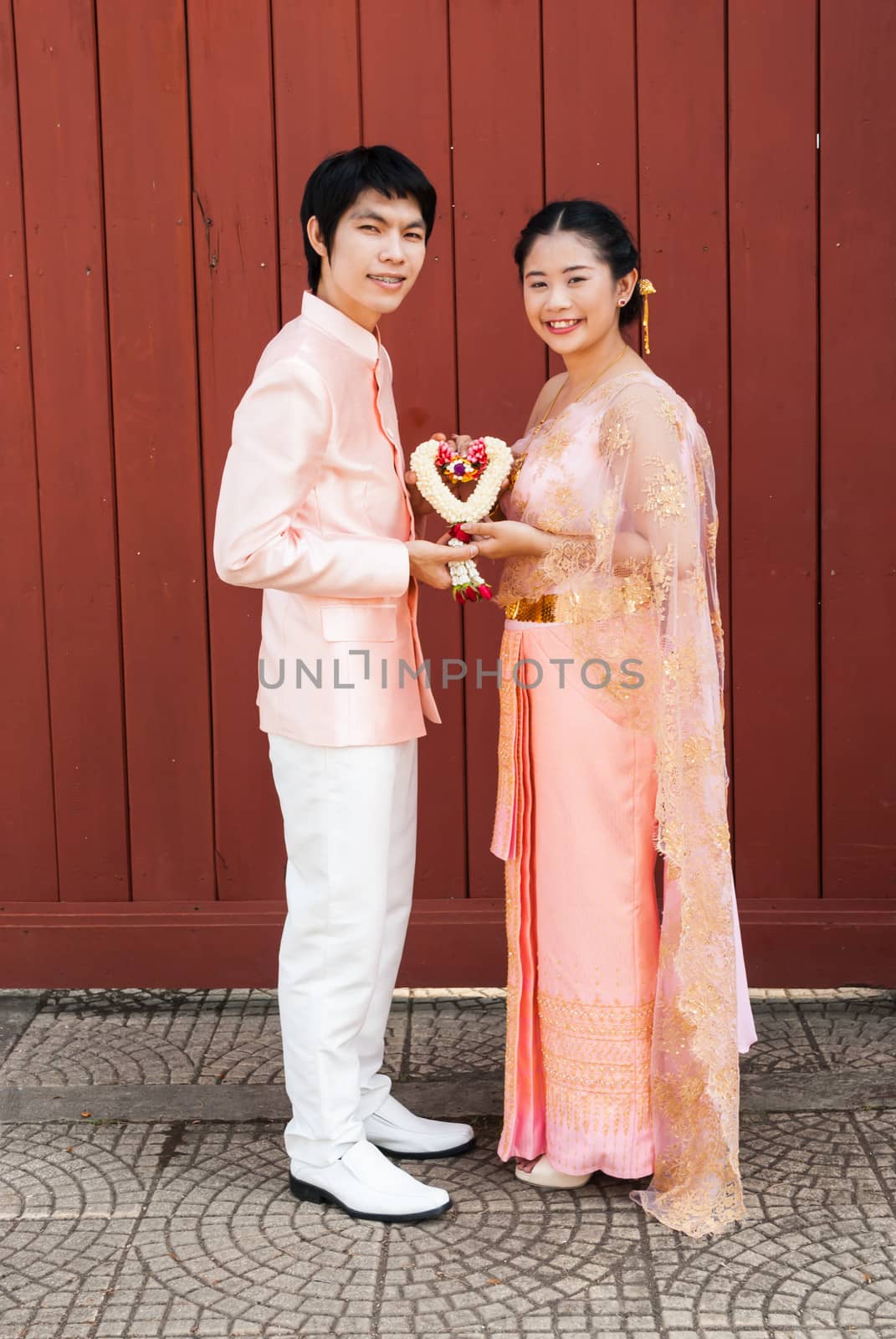 Asian Thai bridal in Thai wedding suit with heart shape flowered garland