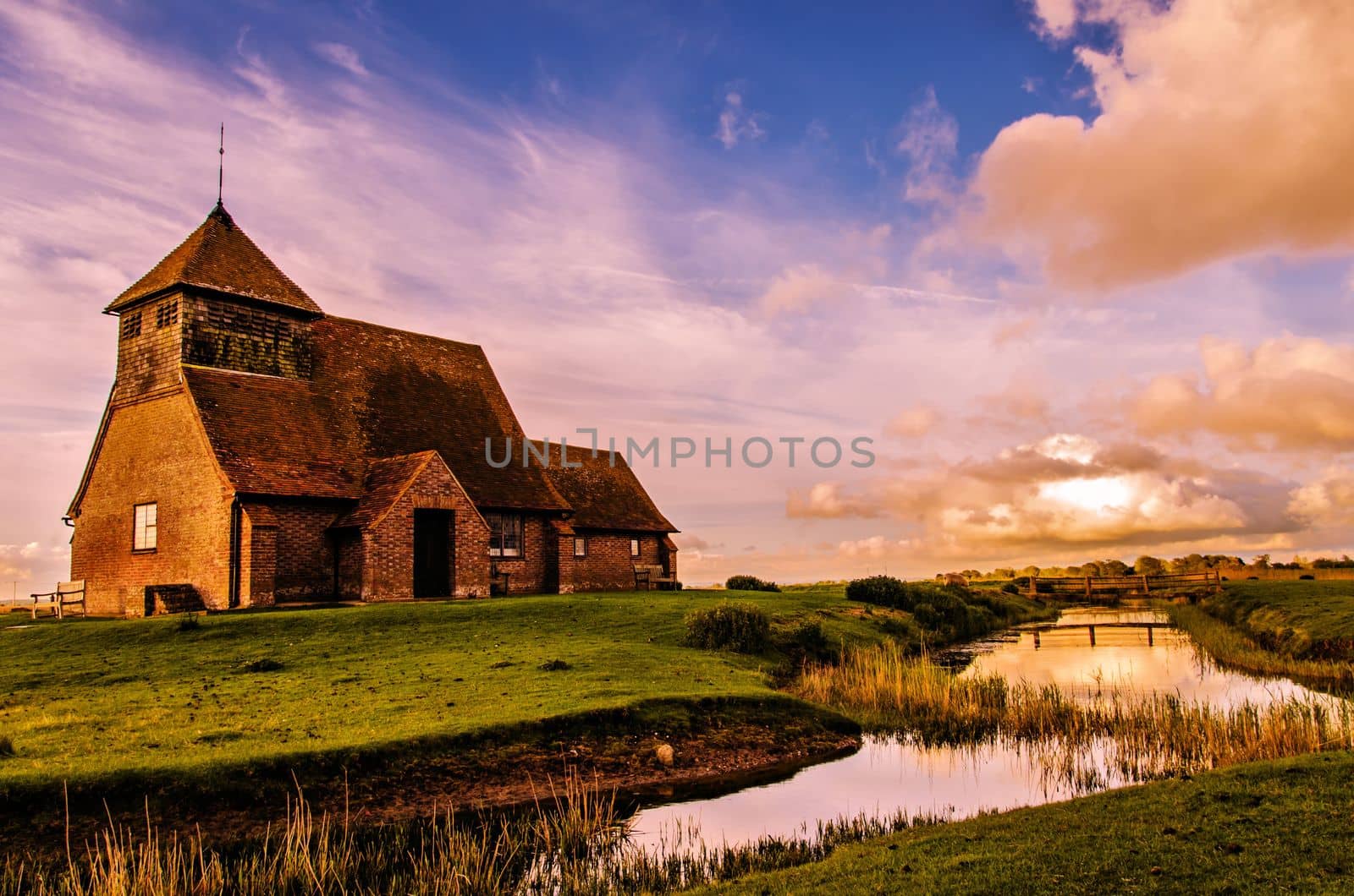 The church of St Thomas a Becket, Fairfield, is a rare example of a small medieval church which has managed to survive without an immediate village to sustain it. It stands remote and isolated on a man-made hillock above the Wallend Marsh, part of Romney Marsh, Kent, UK.

photograph © Jeremy Sage