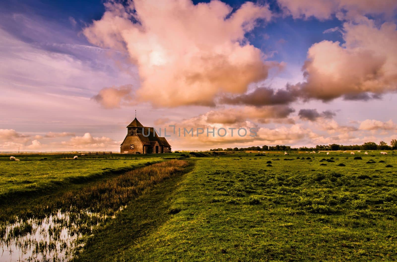 The church of St Thomas a Becket, Fairfield, is a rare example of a small medieval church which has managed to survive without an immediate village to sustain it. It stands remote and isolated on a man-made hillock above the Wallend Marsh, part of Romney Marsh, Kent, UK.

photograph © Jeremy Sage