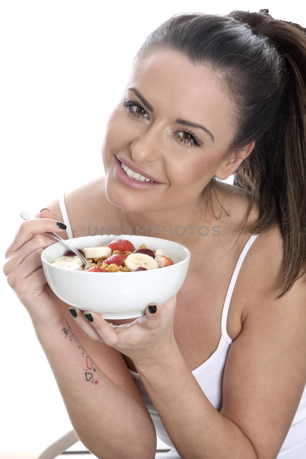Model Released. Young Woman Eating Breakfast Cereal and Fruit by Whiteboxmedia