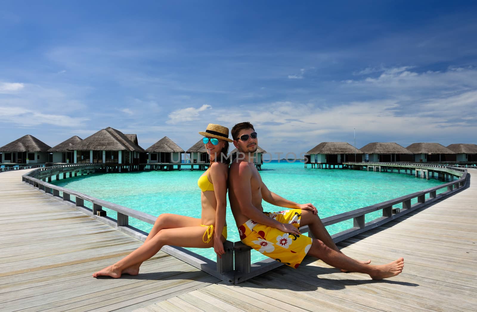 Couple on a tropical beach jetty at Maldives