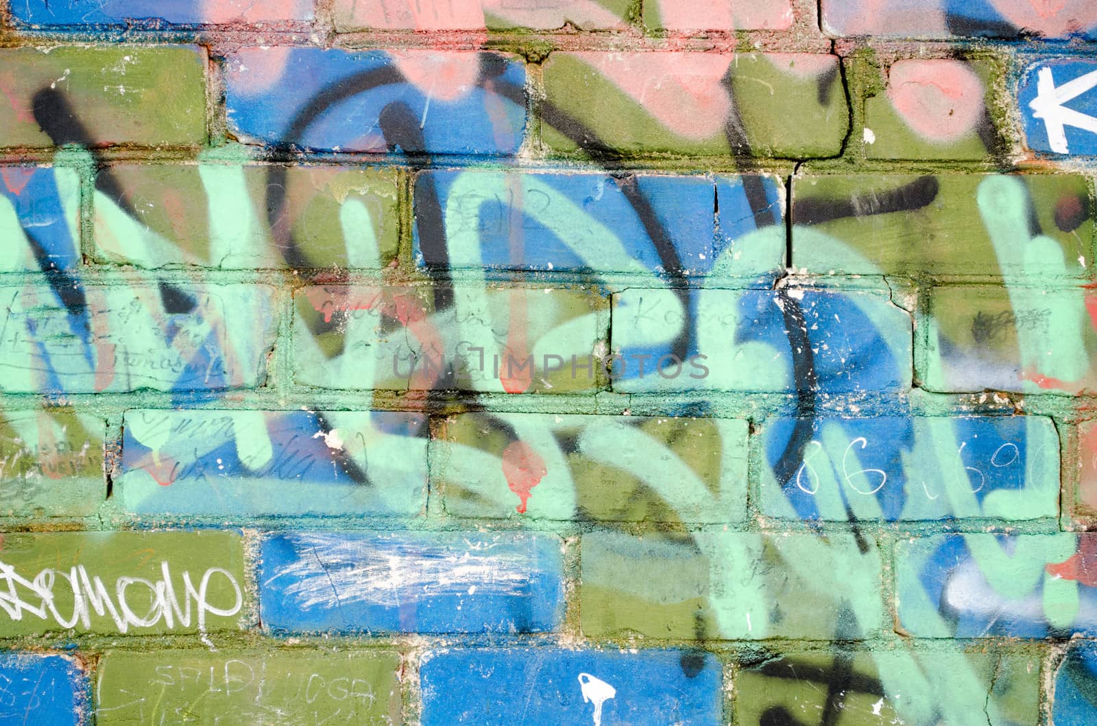 colorful painted brick wall with notes and marks of vandalism. urban background.