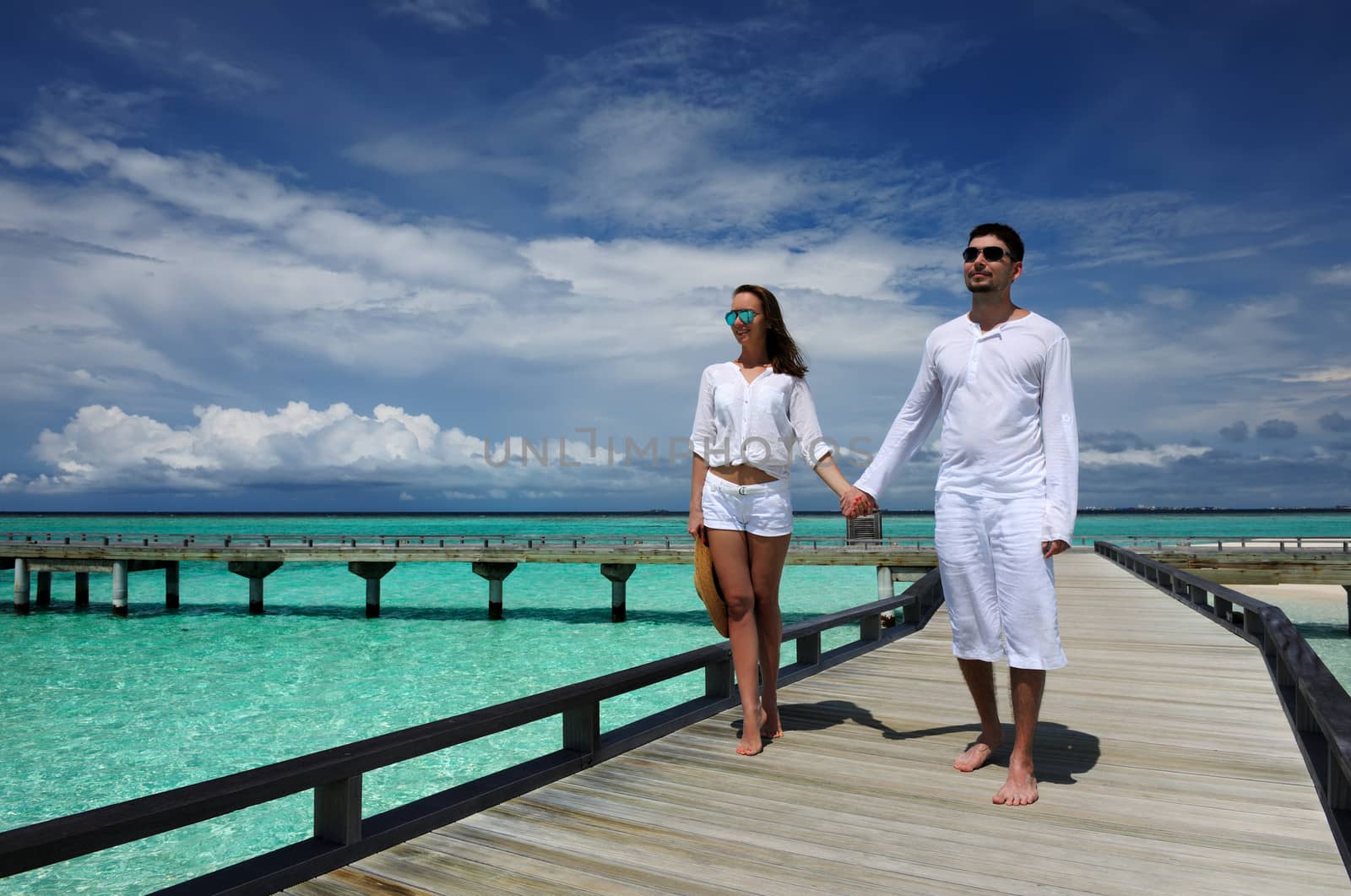 Couple on a beach jetty at Maldives by haveseen