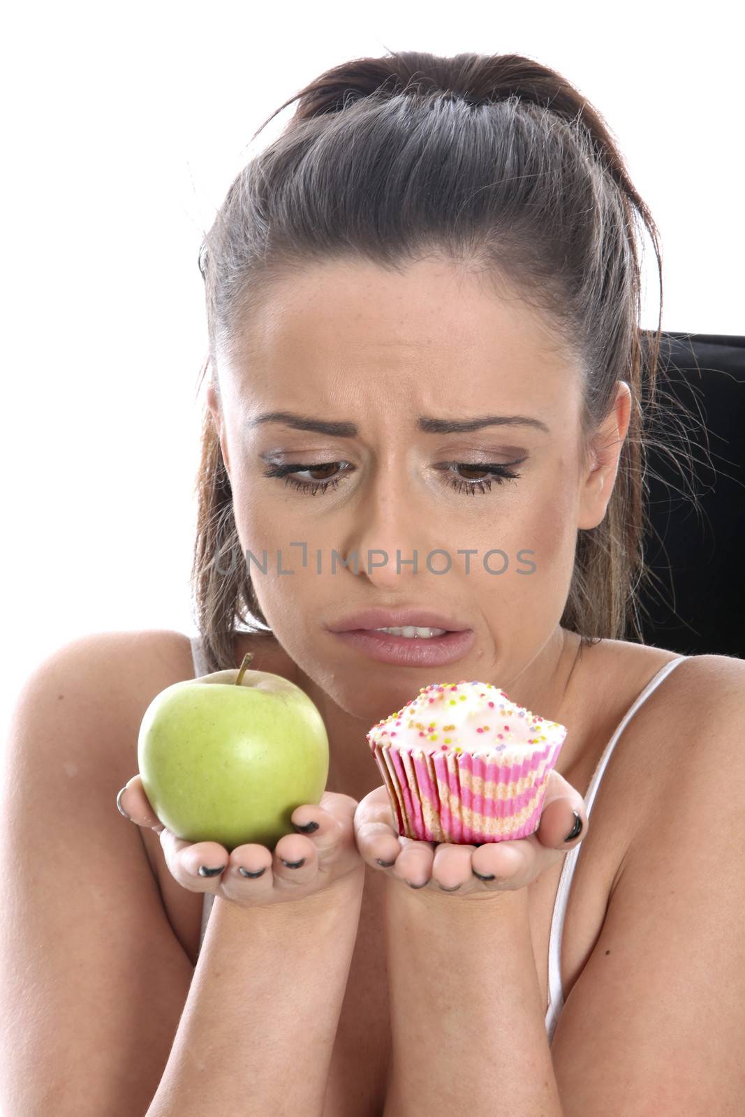 Model Released. Young Woman Comparing Fruit and Cake by Whiteboxmedia