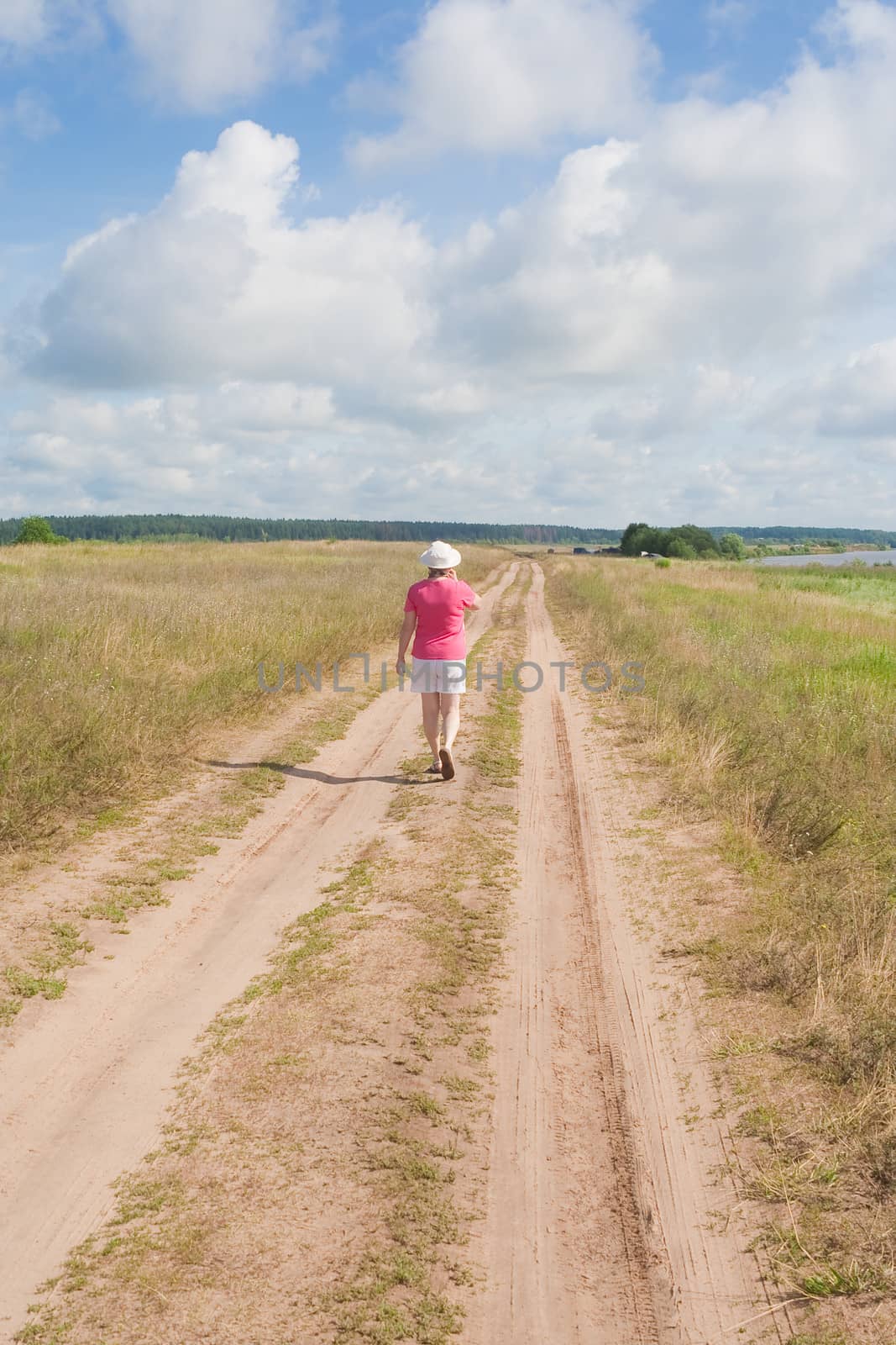 A woman walks along a country road in summer
