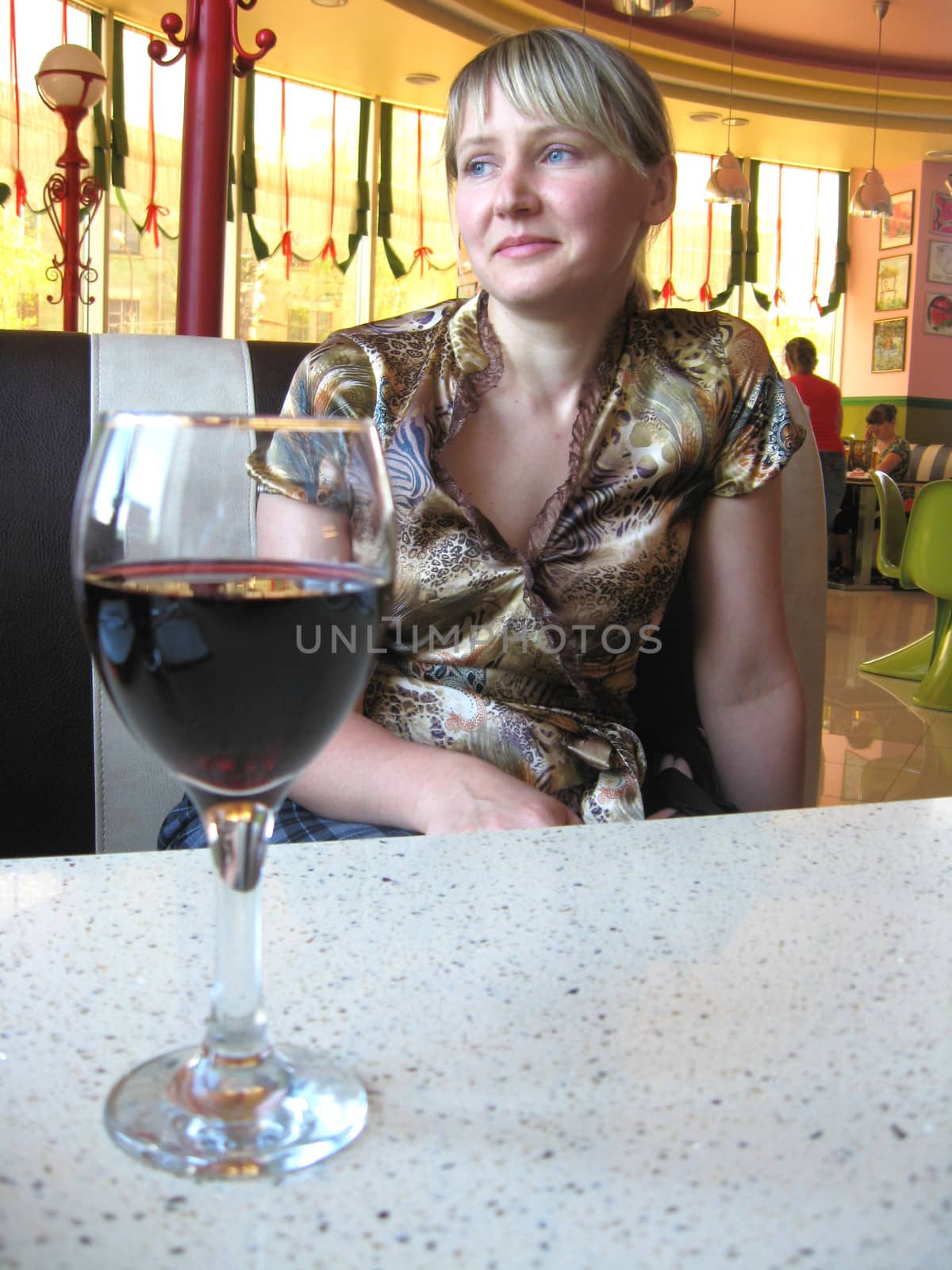 glass of red wine on the table and a girl by alexmak