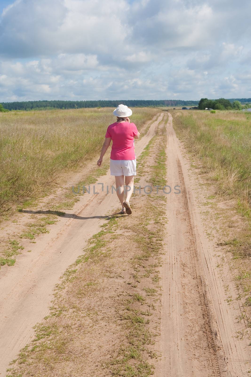 A woman walks along a country road in summer