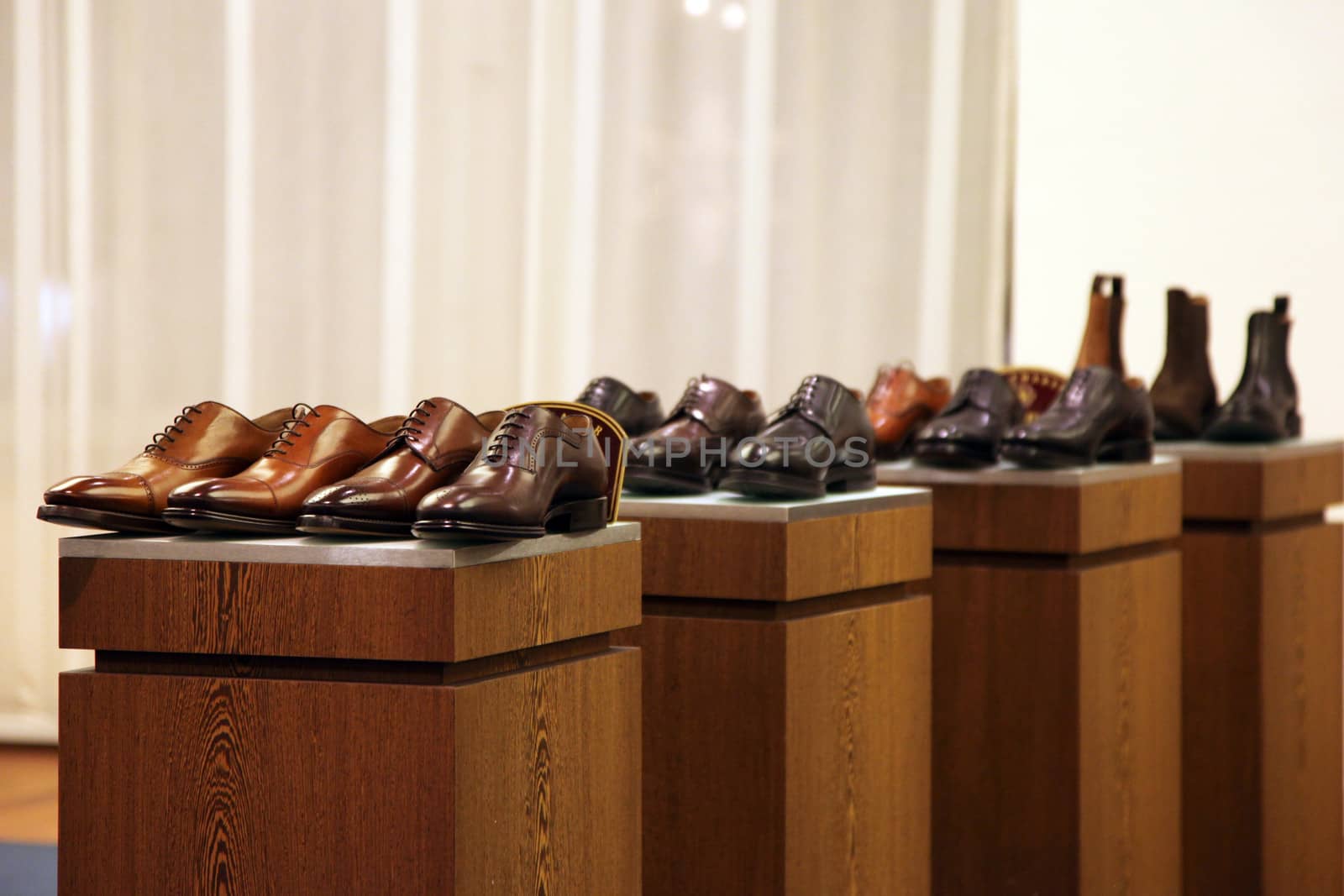 Mens shoes in a store display arranged in neat rows on top of four wooden cabinets