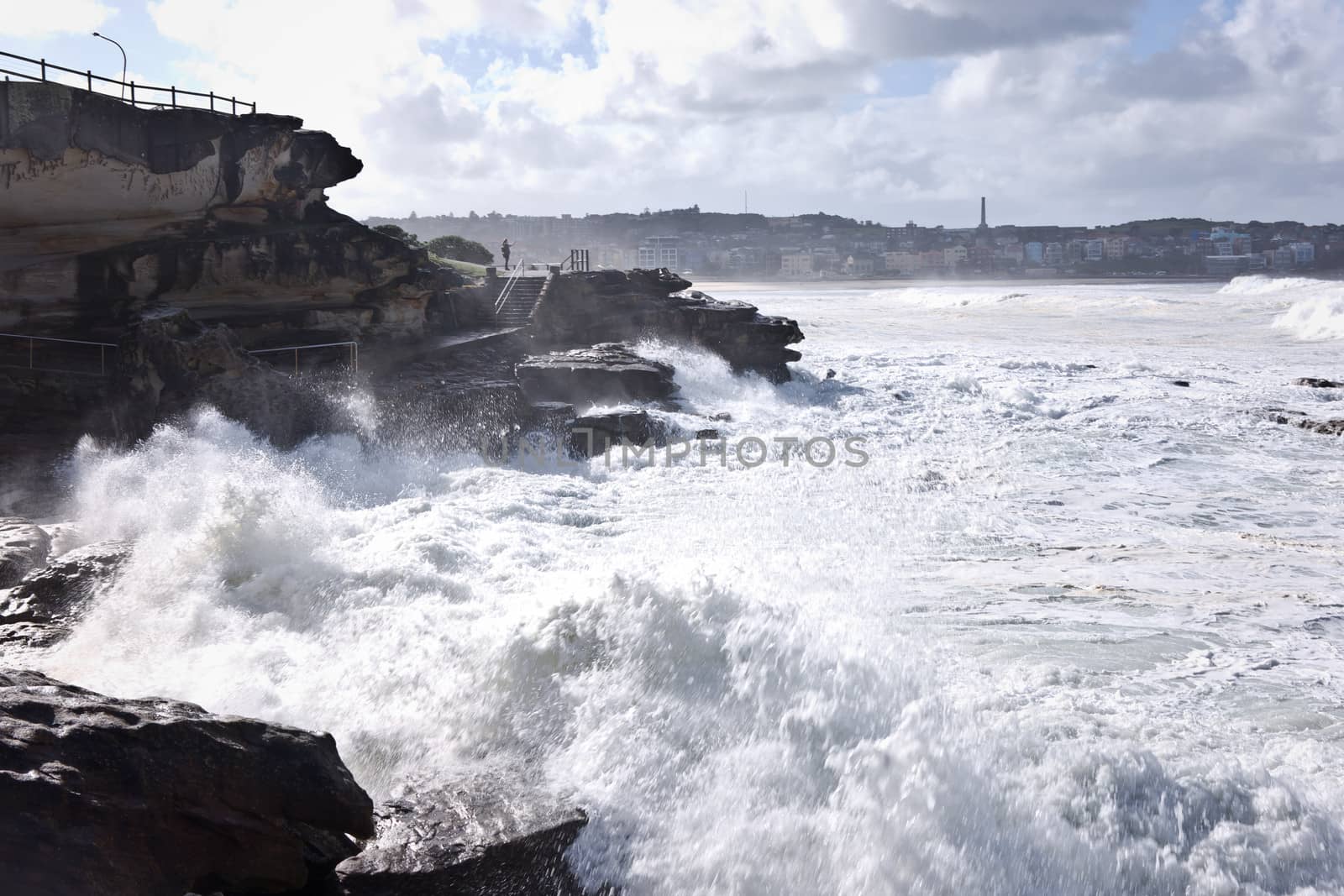 Powerful white waves breaking on a rocky shore at Bondi Beach in Sydney, Australia during a cyclone