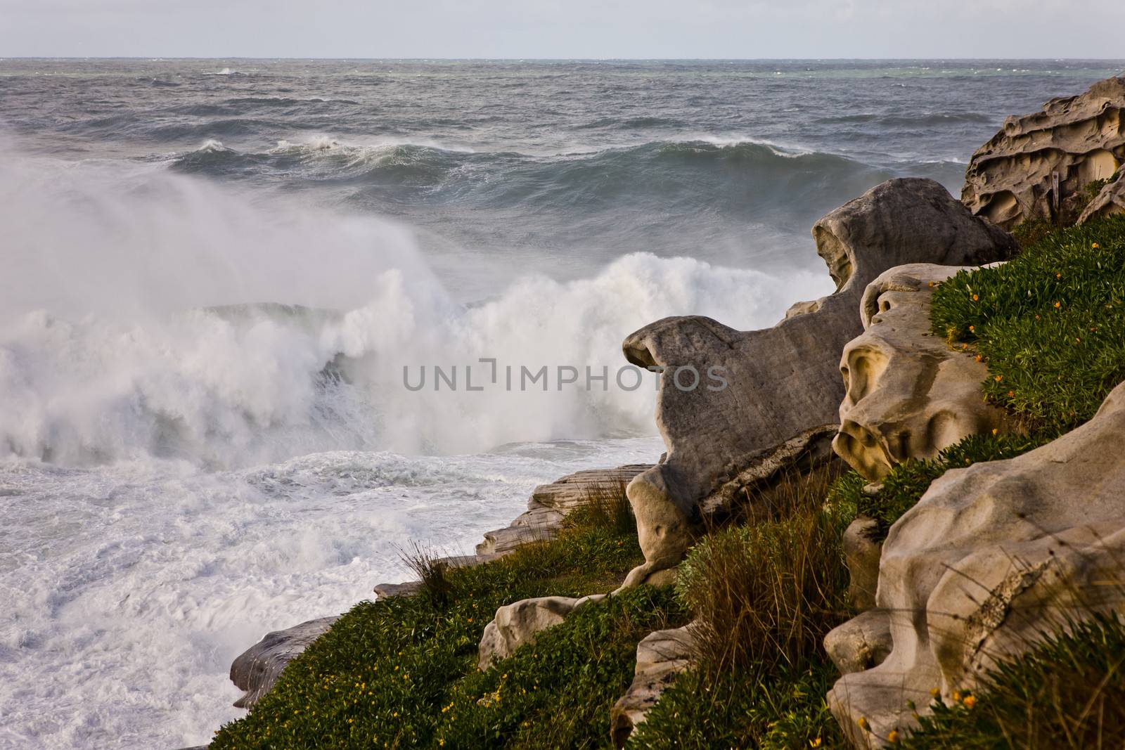 Waves breaking in a cloud of spray on a rocky shoreline with interesting rock formations at Bondi Beach in Sydney, Australia