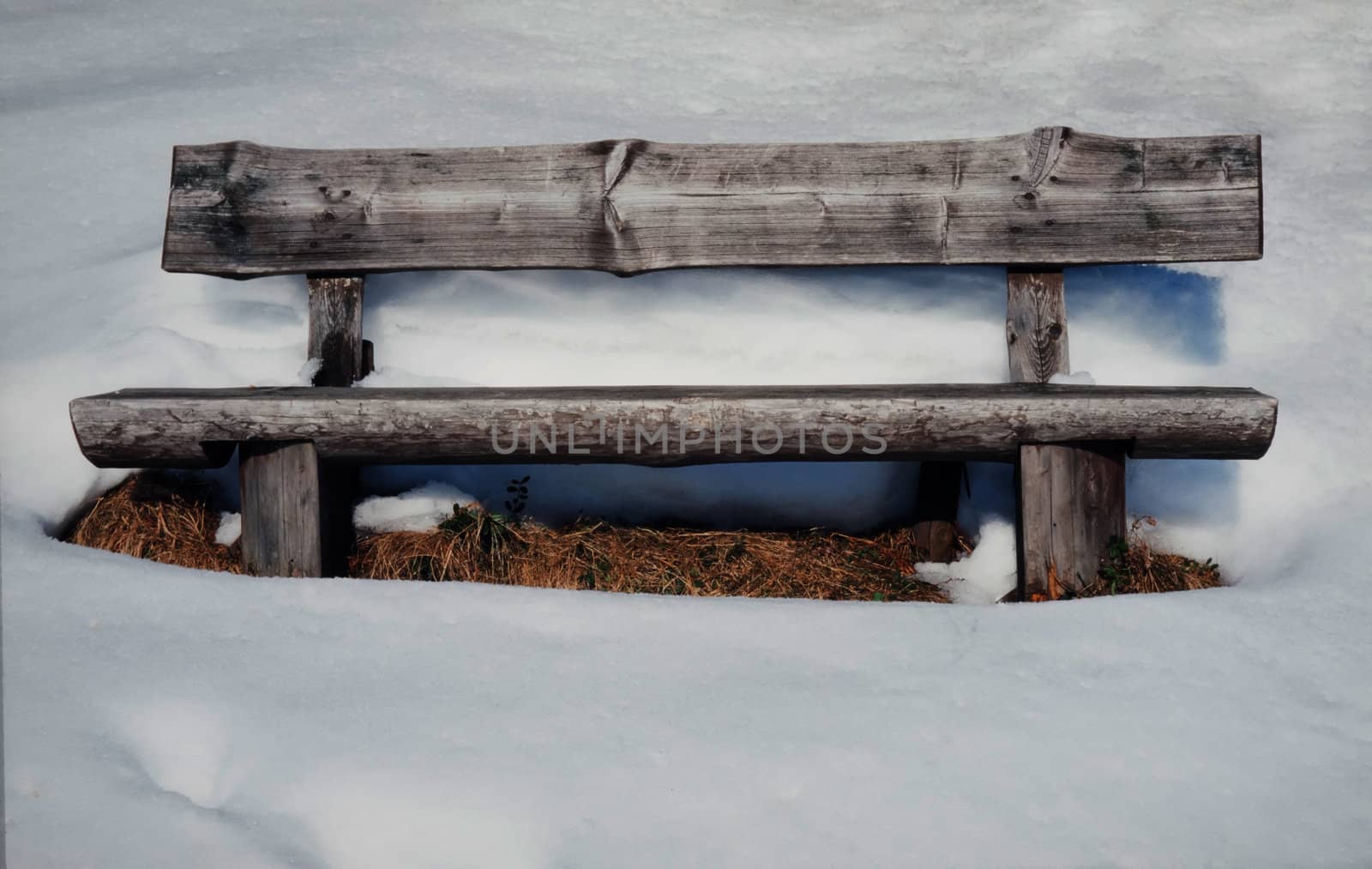 Vacant old rustic wooden bench standing in thick pristine white winter snow