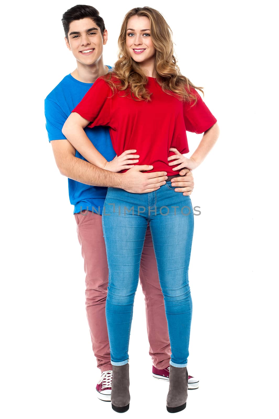 Handsome young man embracing his girlfriend from behind, arms around her waist