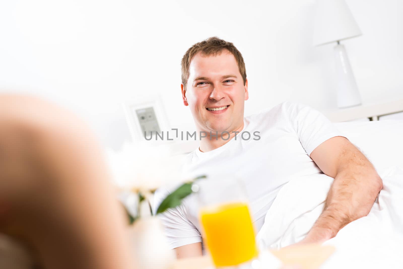 woman brought her boyfriend breakfast in bed, holding a tray of juice and breakfast