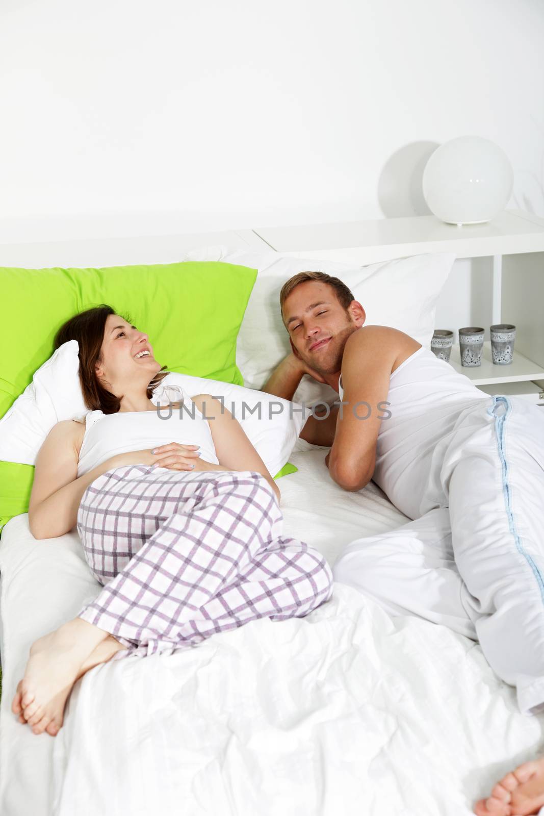 Young couple having a relaxing day lying dozing on their bed with smiles of pleasure