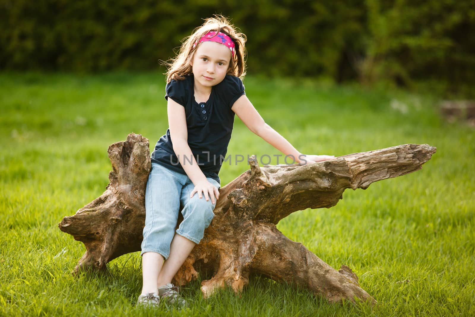 Girl sitting on a tree trunk at the golden hour on a warm summer day