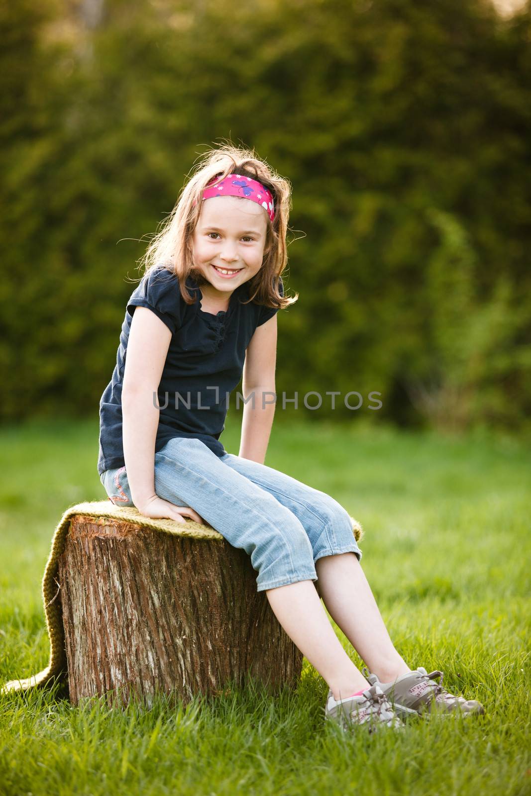 Girl sitting on a tree trunk at the golden hour on a warm summer day