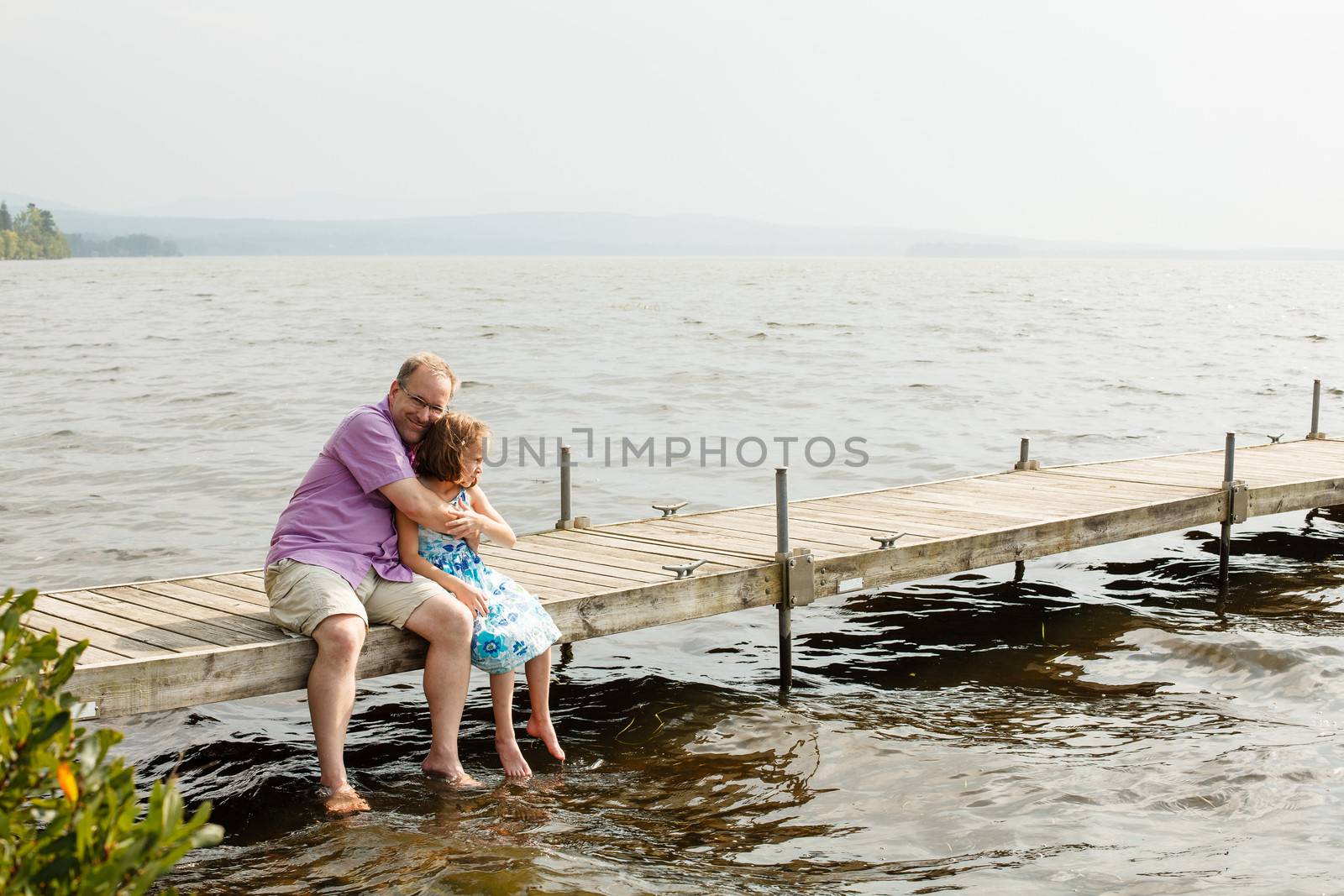 Father and daughter hugging on a wharf by a warm summer day