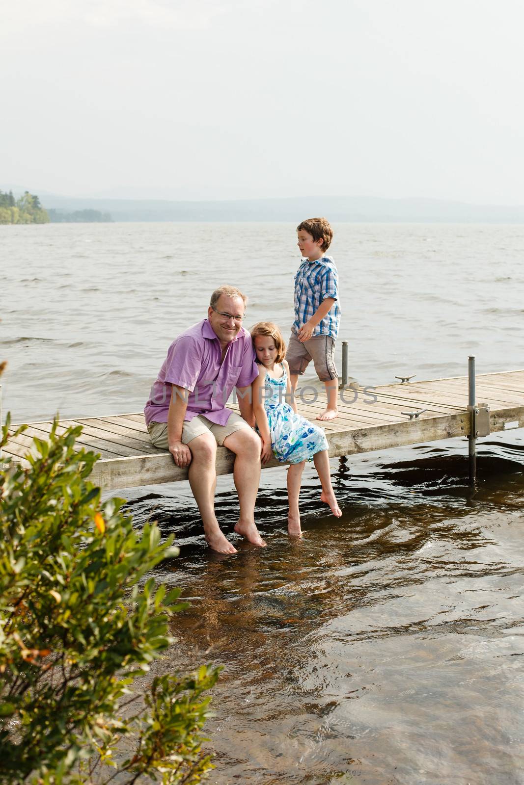 Family sitting and playing on a wharf on a warm summer day