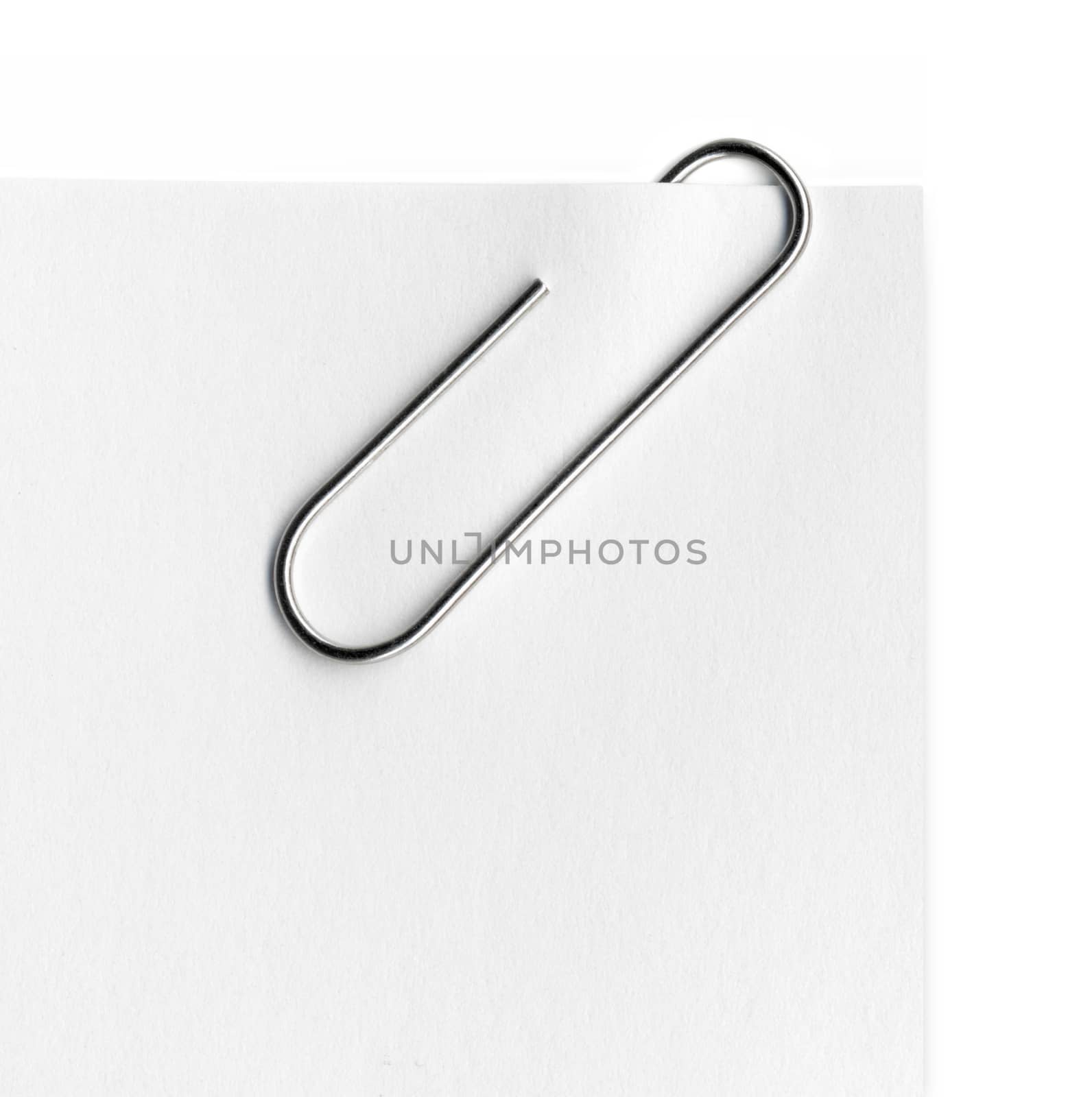 Scanned metal paper clip and paper on white background.