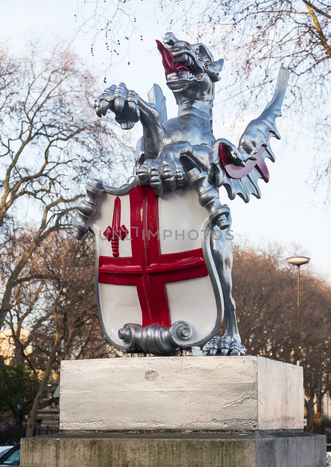 Dragon with red cross on shield marking the boundary of the City of London in England by roadside