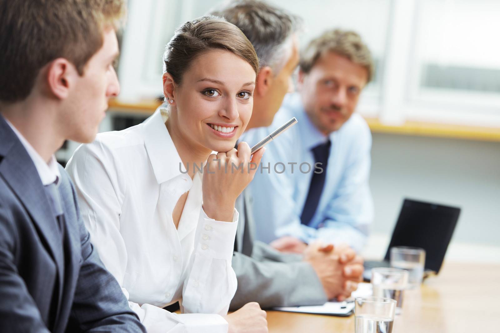 Portrait of a pretty young businesswoman smiling in a meeting with her colleagues in background