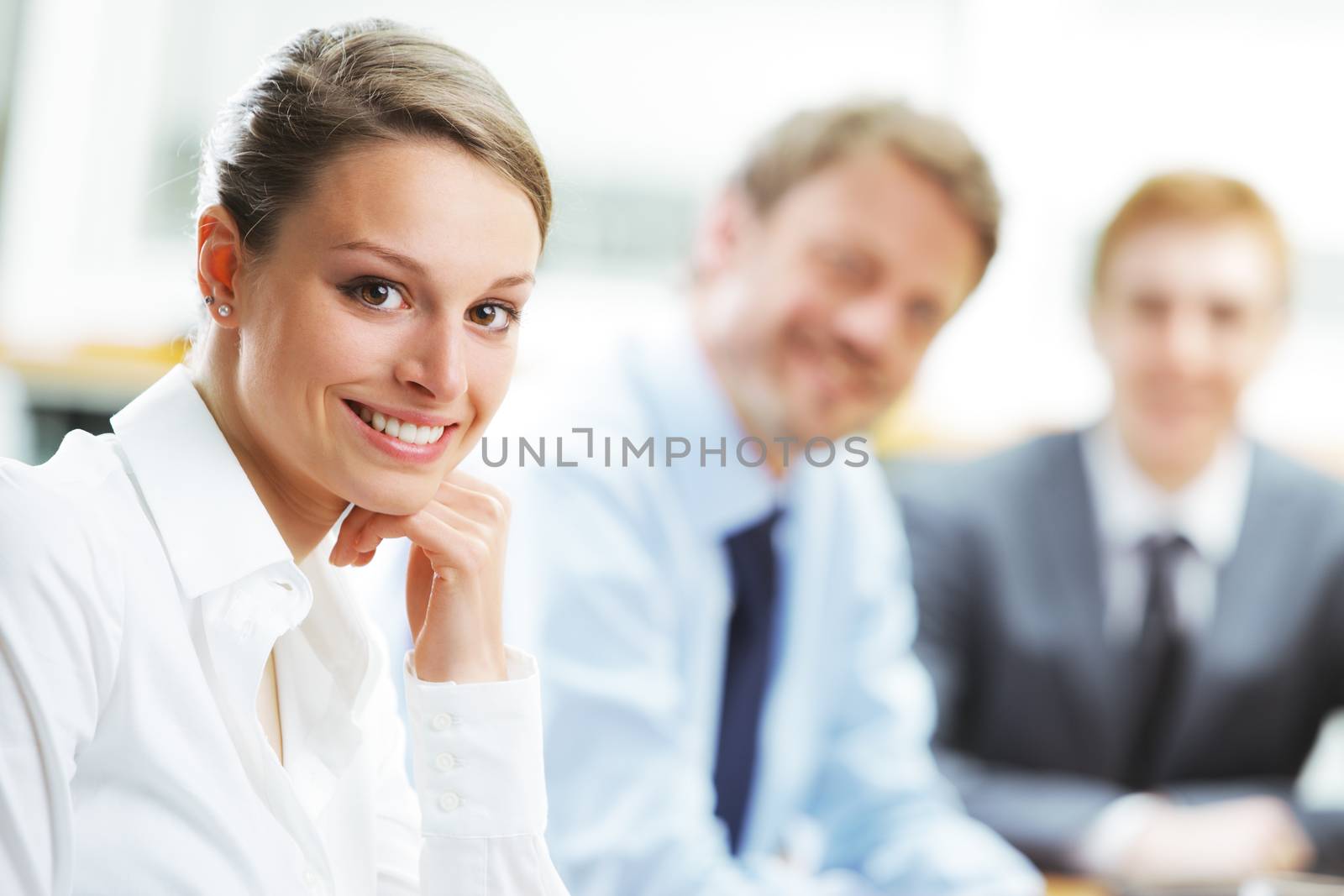 Portrait of a pretty young businesswoman smiling in a meeting with her colleagues in background