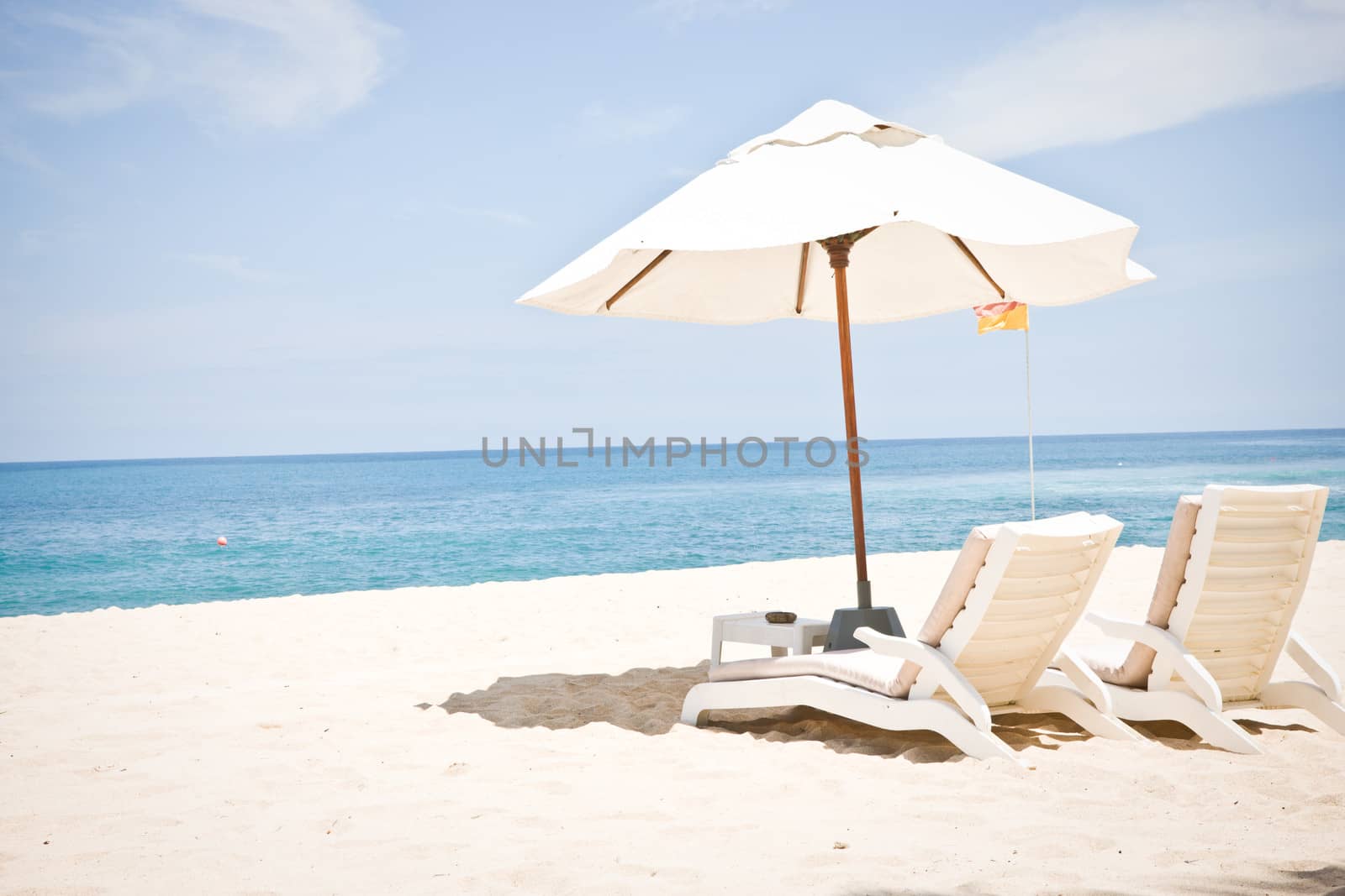 Idyllic beach scene with umbrella and two lounge chairs