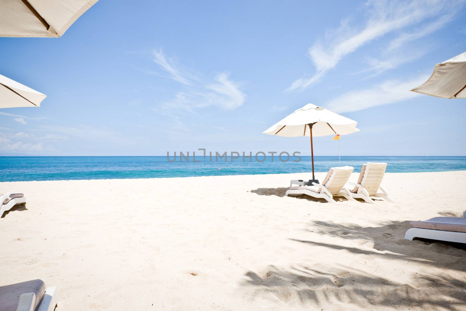 White sand, the ocean and umbrellas with beach chairs